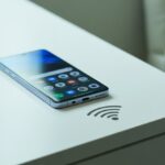 Um smartphone moderno sobre uma superfície branca com um símbolo pequeno de NFC ao lado.